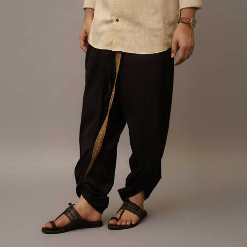 Person wearing black pants with a gold stripe and a beige shirt on a gray background