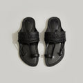 Pair of black sandals on a light gray marble surface